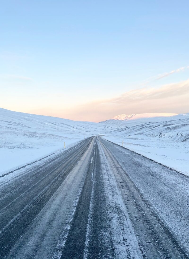 An icy road in Iceland that lies through snowy mountains