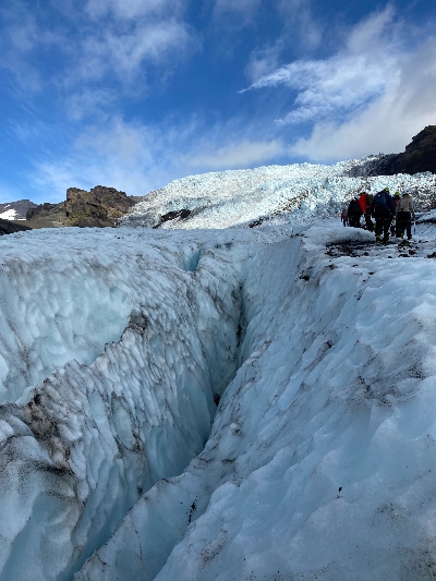 Glacier hikers walk along of a huge crack in Falljokull glacier in Iceland