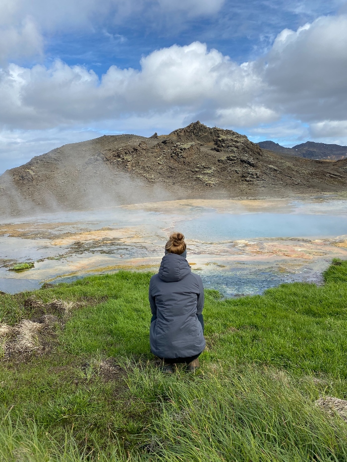 A hiker admiring the colourful environment Hagavikurlaugar in the Hengill area in Iceland