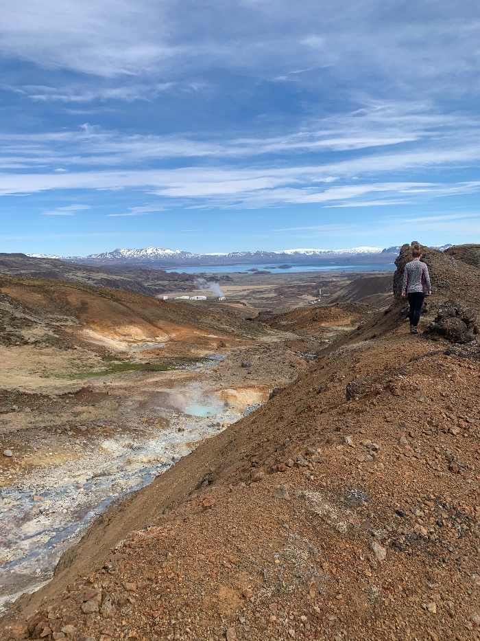 A hiker admiring the view over a geothermal area and lake Thingvallavatn in Iceland
