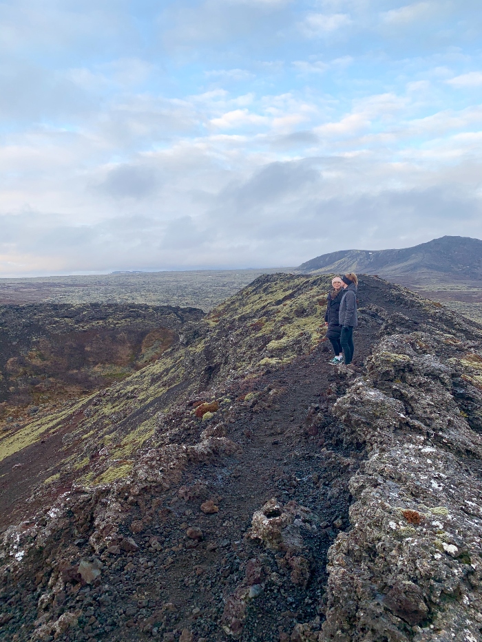 Two hikers admiring the view from the volcanic crater of Burfell in Heidmork Iceland