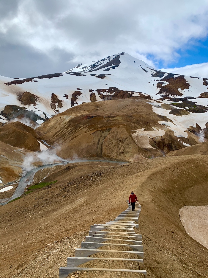 A hiker walking up steps surrounded by rhyolite mountains in Iceland