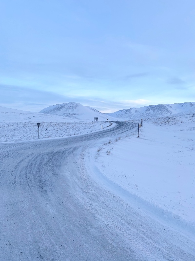 Winding icy road surrounded by snowy ground and mountains