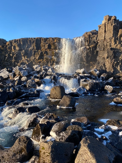 A small waterfall falling down to the rocky ground below in Þingvellir National Park in Iceland