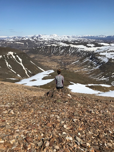 A hiker sitting on a rock and admiring the view from the top of a rhyolite mountain