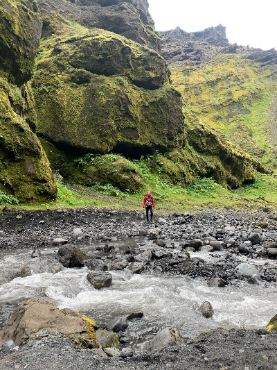 A hiker looking for a good place to cross a river in Stakkholtsgjá Canyon in Iceland