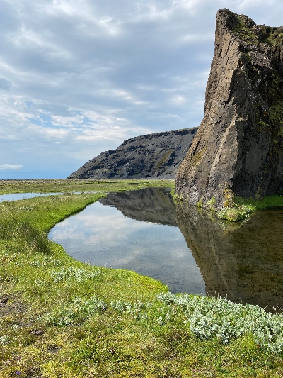 A small pond mirroring a cliff in wonderful summer weather in Iceland