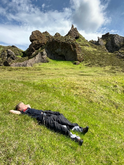 A boy lying in the grass enjoying the sunny weather in Iceland