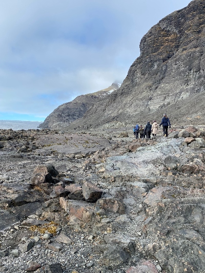 A group of hikers hiking through a rocky terrain to reach a glacier cave