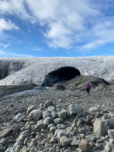 A hiker getting close to a mouth of an glacier cave