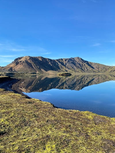 A big lake mirroring the surrounding mountains and blue sky