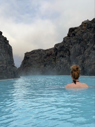 A woman enjoying the warm blue water surrounded by lava walls in the Blue Lagoon Retreat
