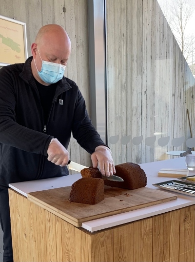 A man cutting a fresh baked rye bread to slices at Fontana Geothermal Bakery