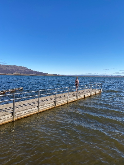 A woman in her swimsuit wondering if she should dive into the cold lake
