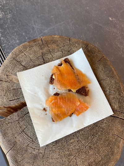 Two slices of rye bread with butter and salmon lying on a piece of wood