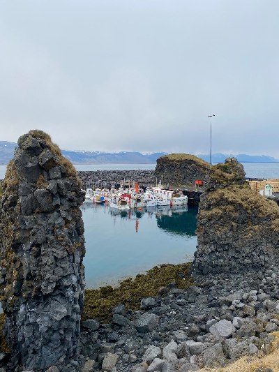 A few small white fishing boats docket in a harbour surrounded by lava cliffs