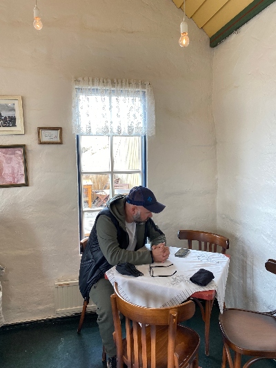 A man sitting by a table inside Fjöruhúsið Café at Hellnar