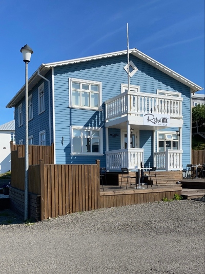 A two story old timber house in Iceland with a brown patio