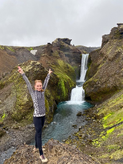 A very happy hiker standing in the front of the last waterfall on the Skógafoss Waterfall Hike in Iceland