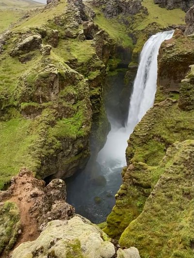 A small waterfall falling into a moss covered and very narrow gorge on the Skógafoss Waterfall hike in Iceland