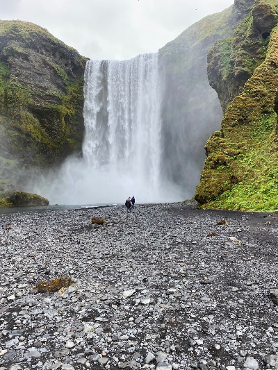 Two people walking towards Skógafoss Waterfall in Iceland