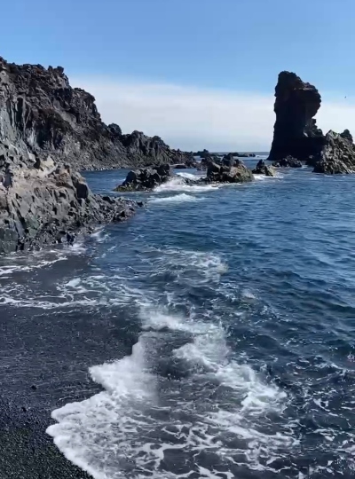 Blue ocean, black gravel and lava sculptures on Djúpalónssandur black beach in Iceland