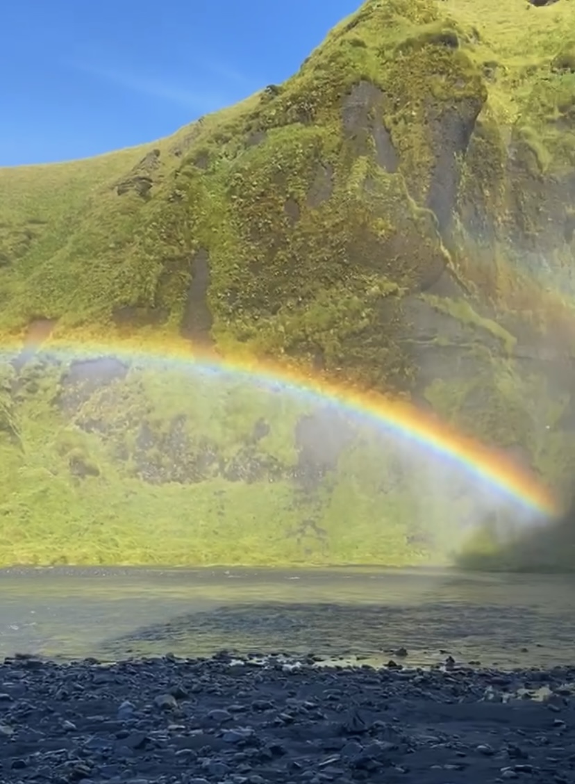 A rainbow in front of Skógafoss waterfall on a sunny day in Iceland