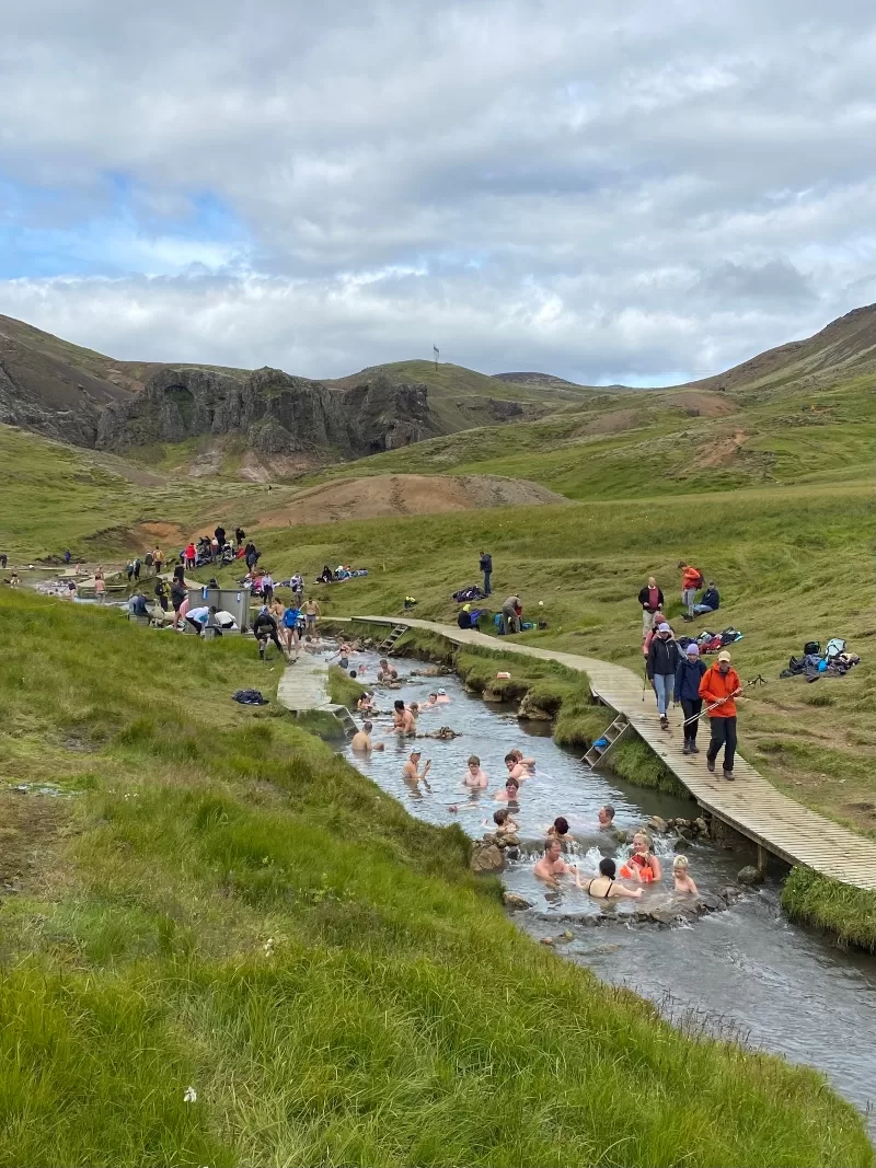 The warm river in Reykjadalur Iceland packed with people bathing in it on a summer day