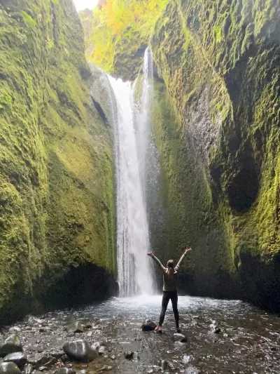 A womand standing at in front of the waterfall at the end of Nauthúsagil Gorge