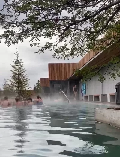 People enjoying the warm water and a drink in Forest Lagoon Iceland