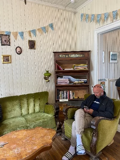 A bold man sitting in cozy café called Simbahöllin that is decorated like an old Icelandic living room.