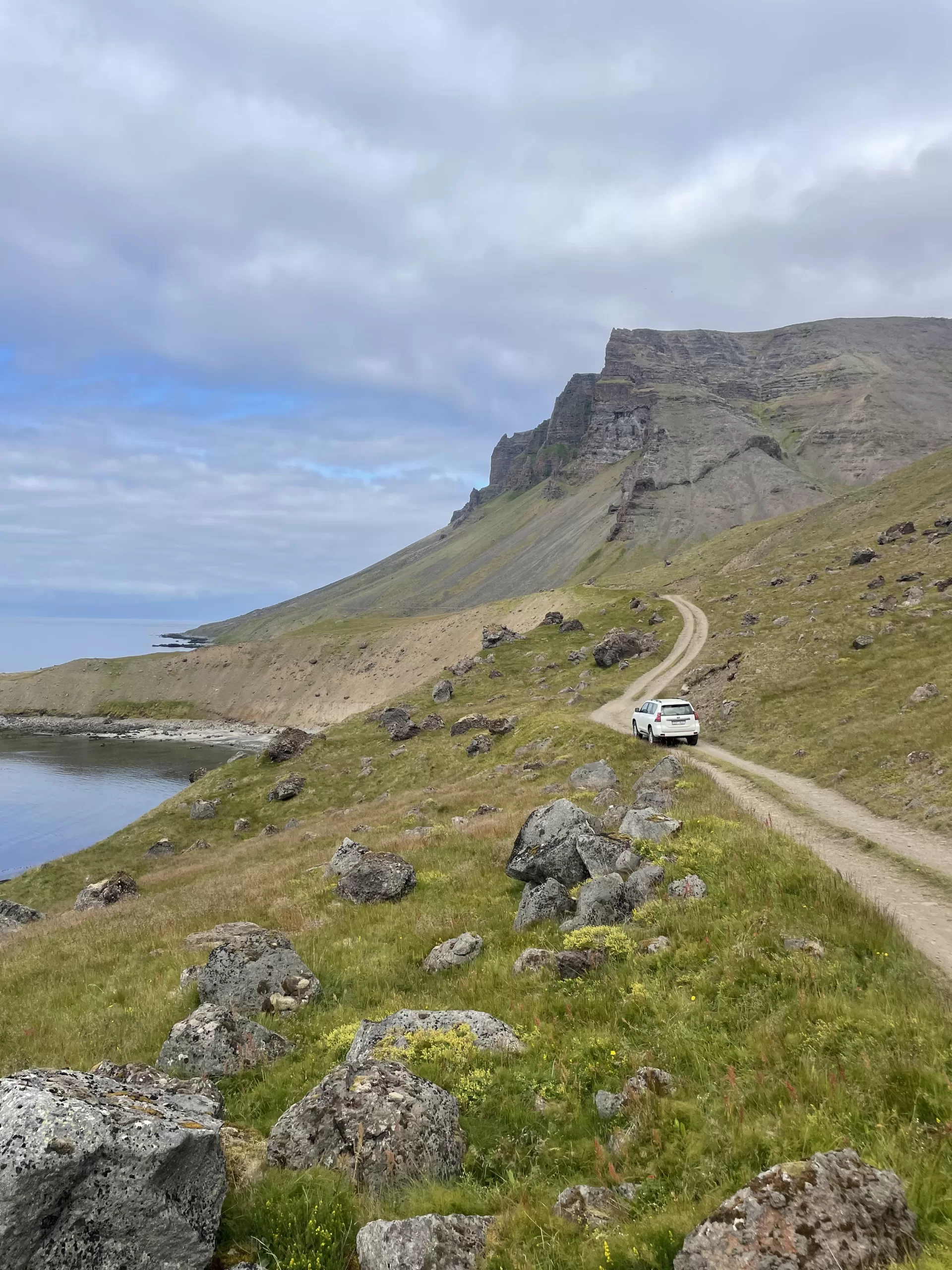 A jeep on a narrow gravel road called Svalvogavegur along a coast line in Iceland