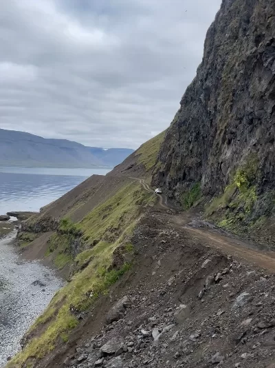 A narrow gravel road called Svalvogavegur in the mountain side of a hight mountain in the Westfjords Iceland
