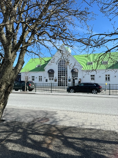 Big white house with a green roof in Selfoss with a tree in the foreground